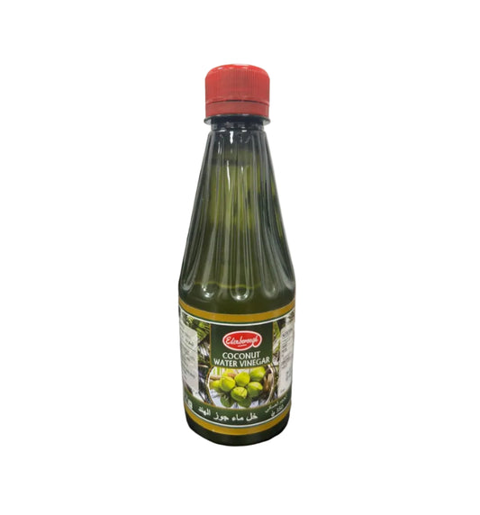 Bottle of coconut water vinegar with a red cap on a dark surface.